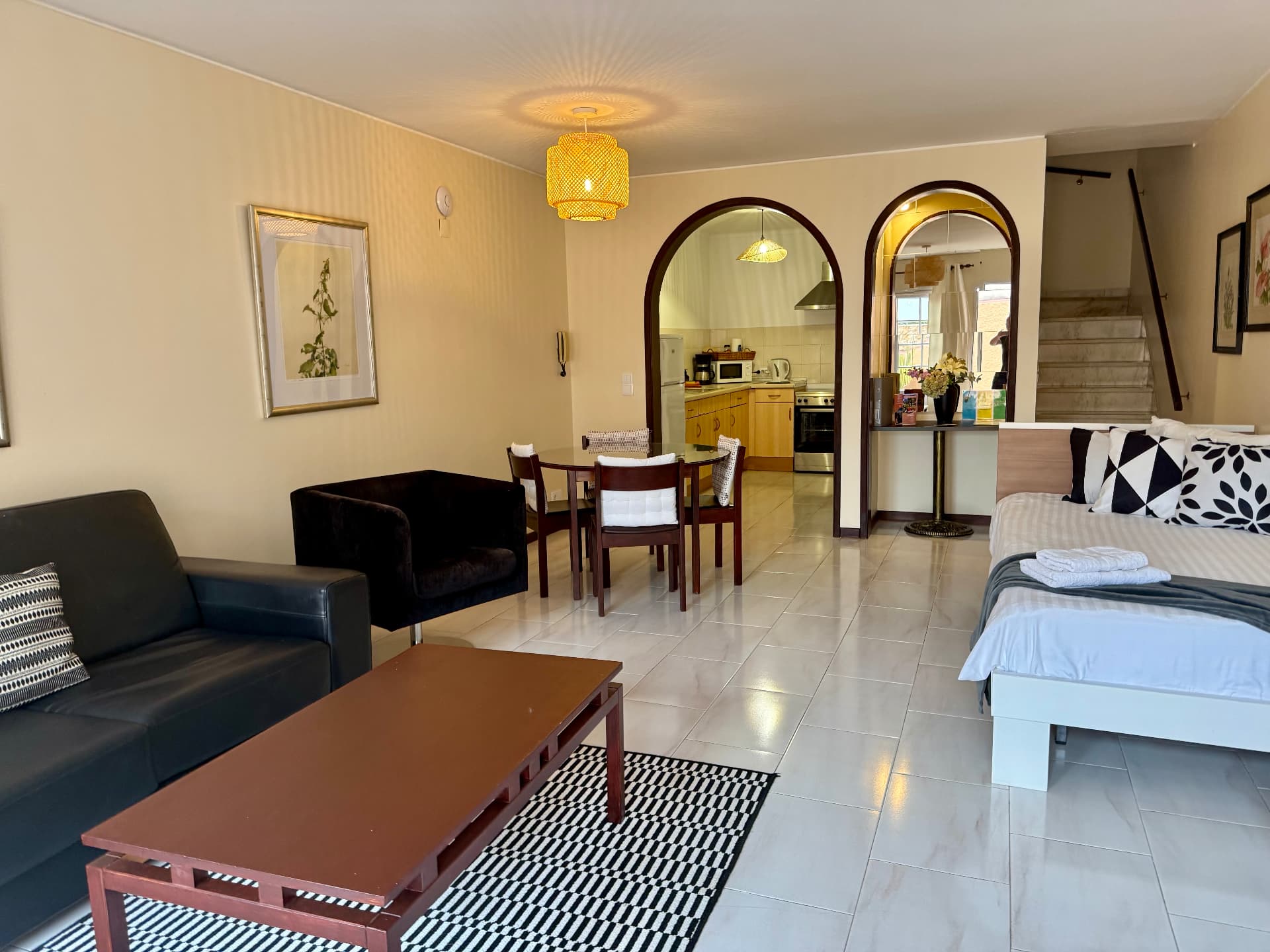 Family Villa living area with black sofa, dining table and arched kitchen doorway